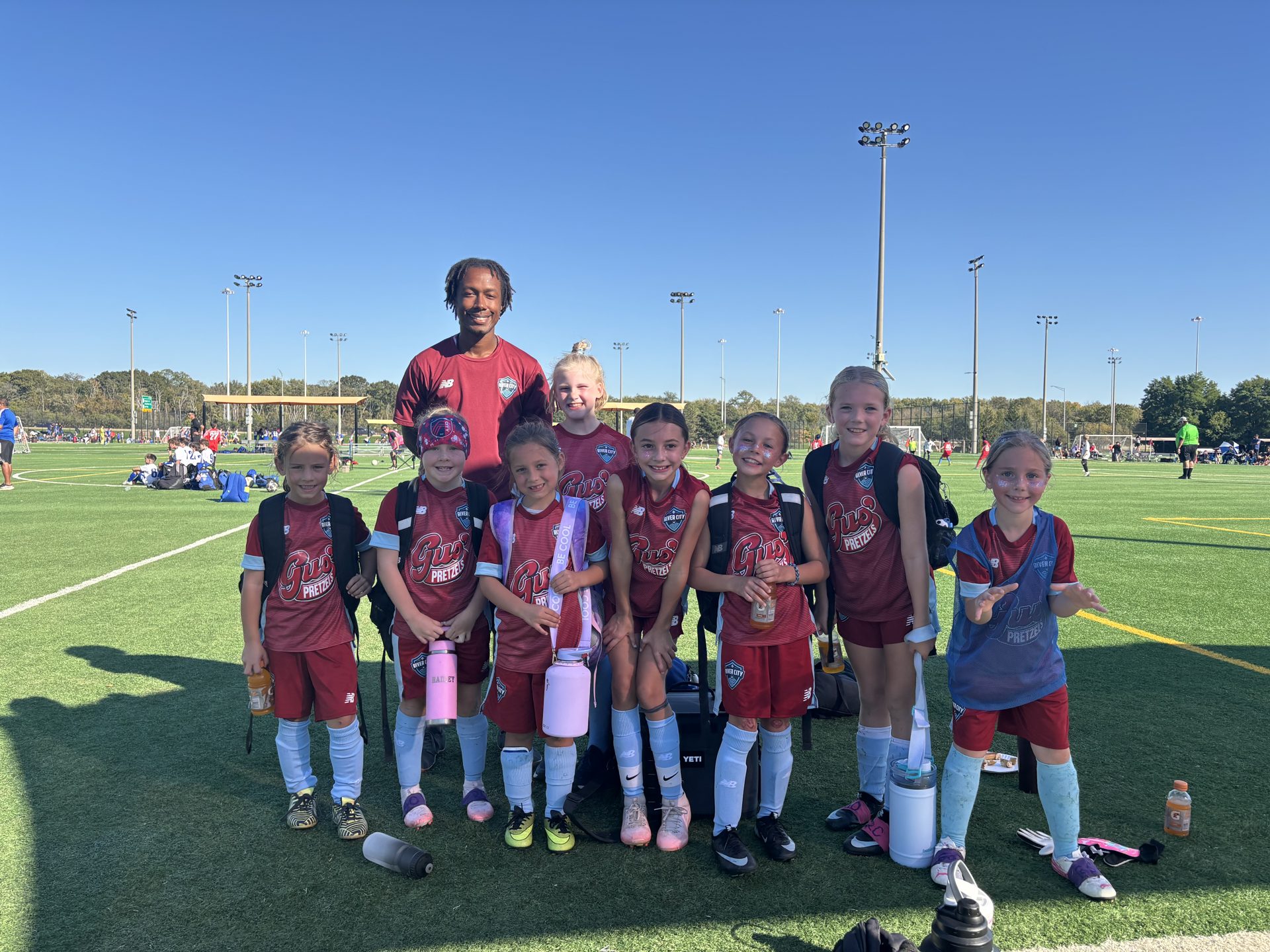 River City FC girls team and coach in maroon kits on the turf